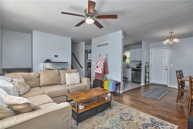 living room with ceiling fan with notable chandelier, wood finished floors, and visible vents
