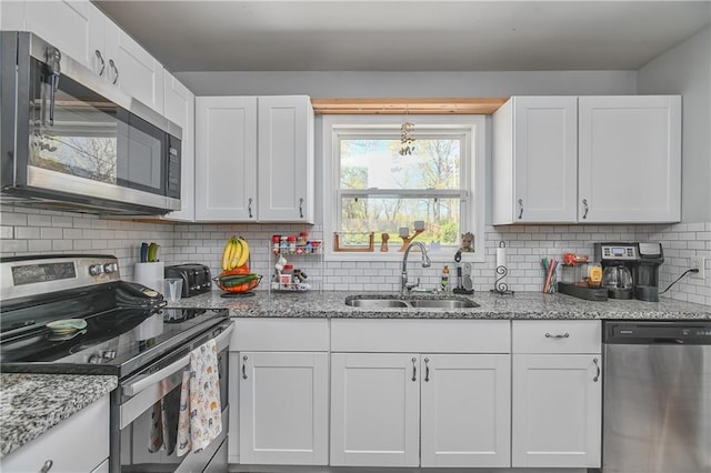 kitchen featuring white cabinets, decorative backsplash, a sink, and appliances with stainless steel finishes