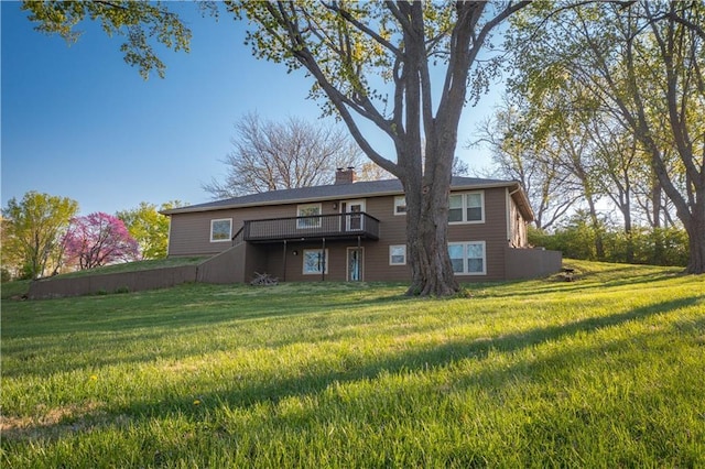 rear view of property featuring a wooden deck, a lawn, and a chimney