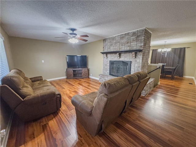 living area featuring wood finished floors, ceiling fan with notable chandelier, and baseboards