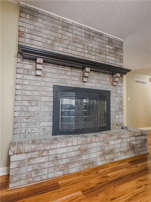 interior details with a fireplace, visible vents, baseboards, and wood finished floors