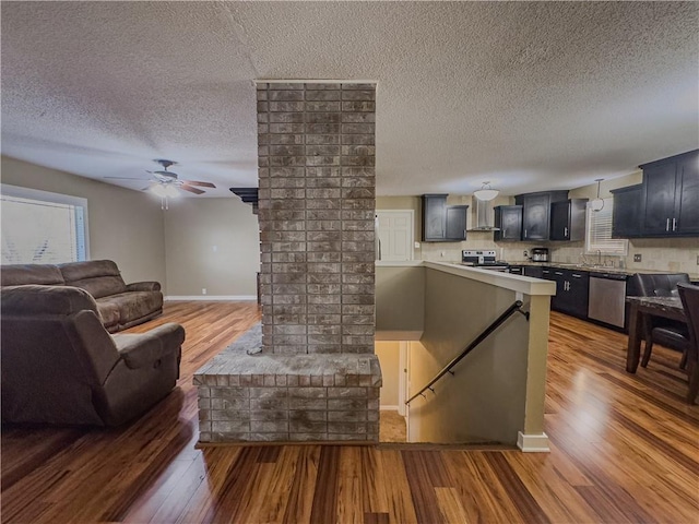 living room featuring light wood-style floors, ceiling fan, baseboards, and a textured ceiling