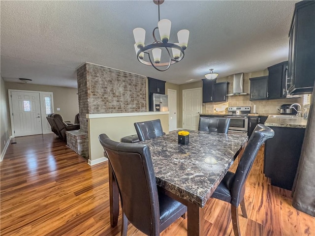 dining space with a chandelier, a textured ceiling, baseboards, and wood finished floors