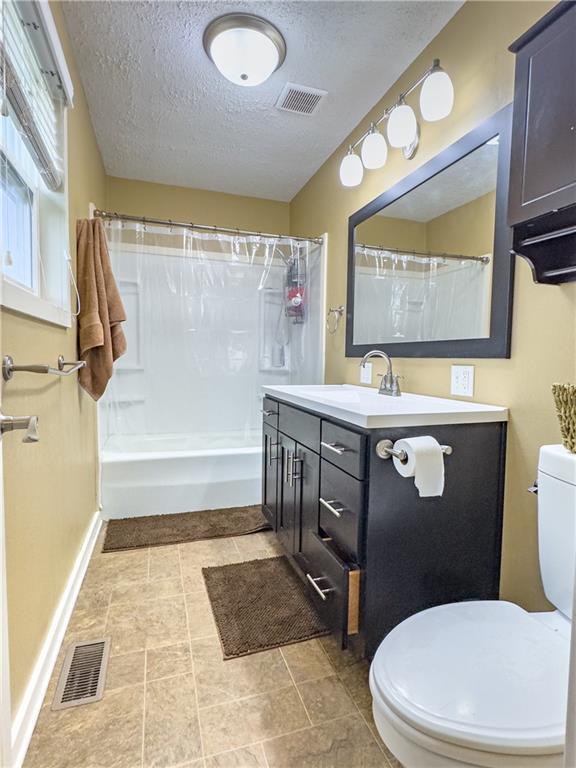 full bathroom featuring vanity, visible vents, a textured ceiling, and toilet