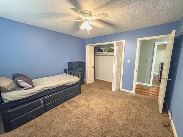 carpeted bedroom featuring a textured ceiling, a closet, baseboards, and a ceiling fan