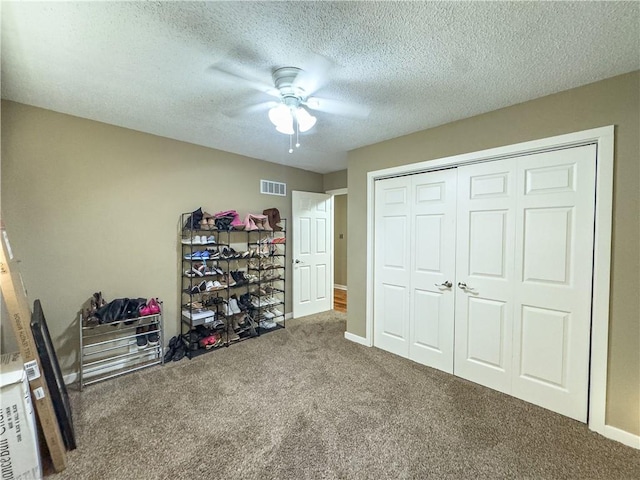 bedroom with ceiling fan, a textured ceiling, a closet, visible vents, and carpet floors