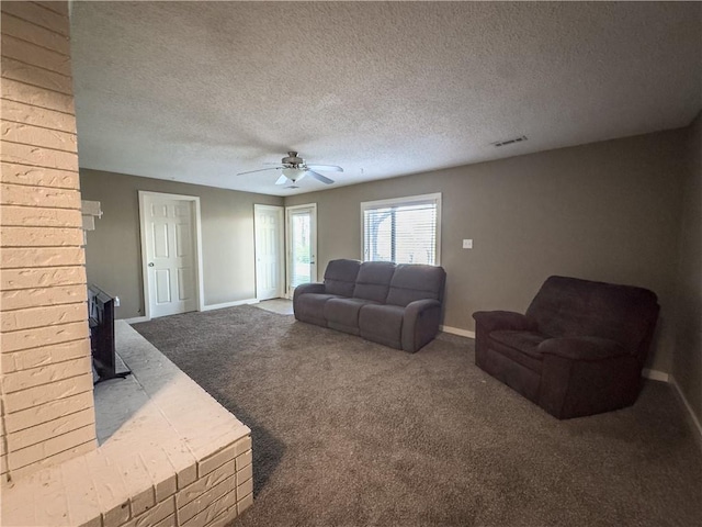 carpeted living room featuring a wood stove, visible vents, baseboards, and ceiling fan
