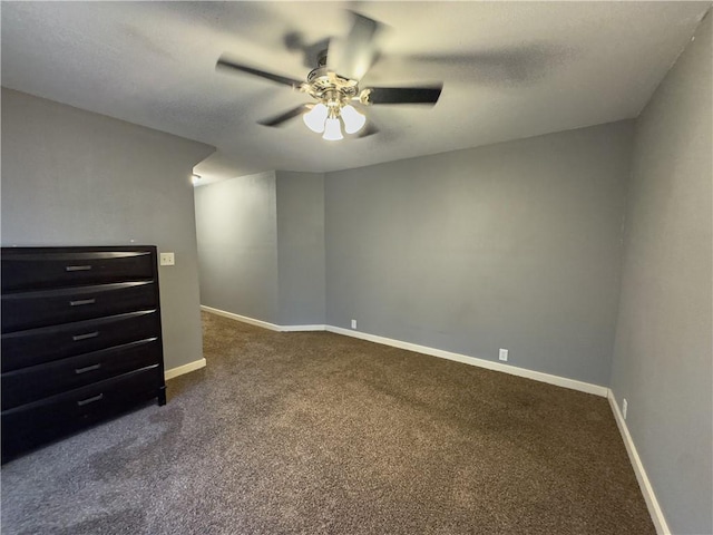spare room featuring dark carpet, baseboards, a ceiling fan, and a textured ceiling