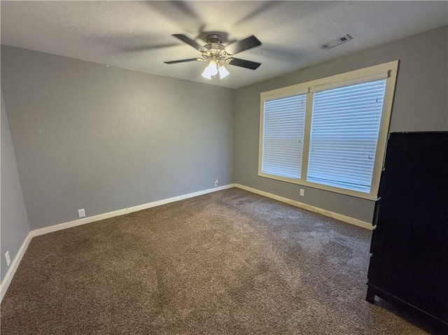 unfurnished room with visible vents, baseboards, a ceiling fan, and dark colored carpet