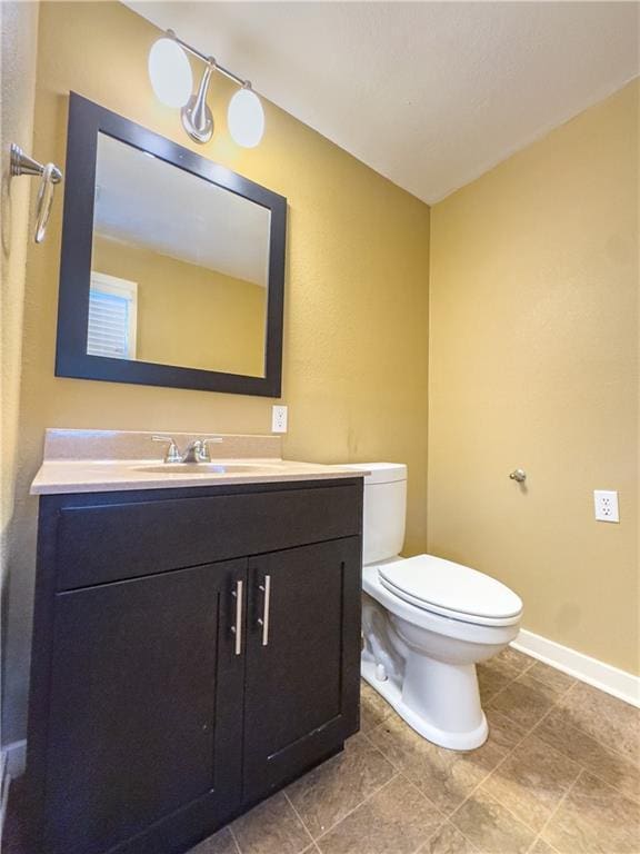 bathroom with tile patterned floors, vanity, baseboards, and toilet