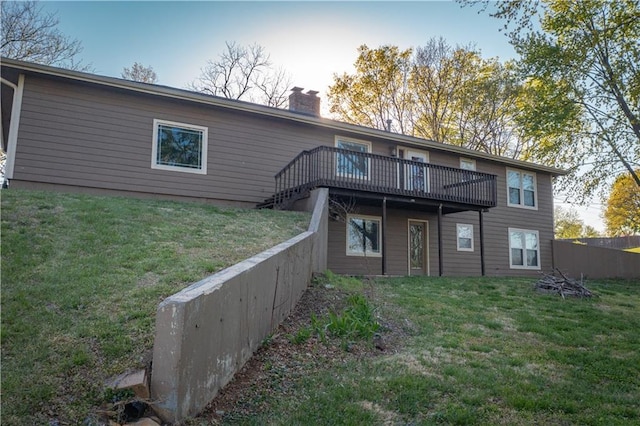 back of house featuring fence, a deck, a lawn, and a chimney