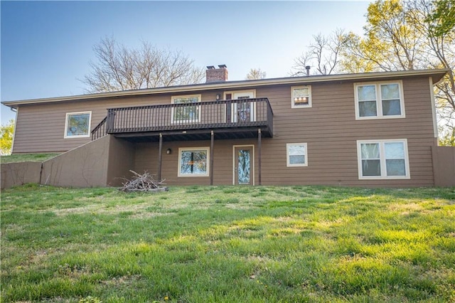 back of property with a wooden deck, a lawn, and a chimney