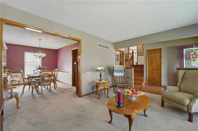 living area featuring a textured ceiling, visible vents, a notable chandelier, light carpet, and stairs