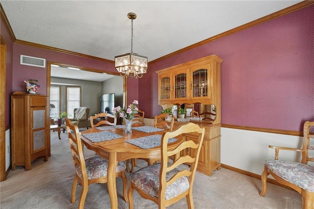 dining room featuring crown molding, a notable chandelier, light colored carpet, baseboards, and visible vents