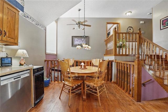 dining area with light wood-style floors, ceiling fan, stairway, and a textured ceiling