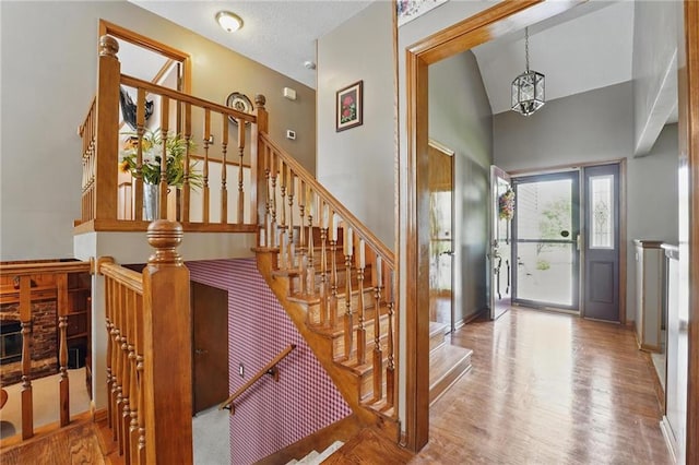 foyer featuring baseboards, a high ceiling, wood finished floors, and stairway