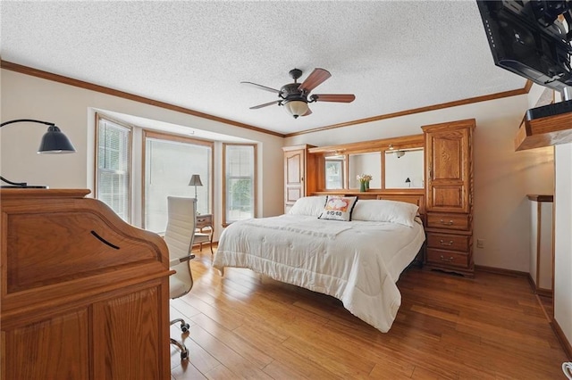 bedroom featuring a textured ceiling, ornamental molding, baseboards, and light wood finished floors