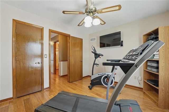workout room with a ceiling fan, baseboards, visible vents, and light wood-style flooring