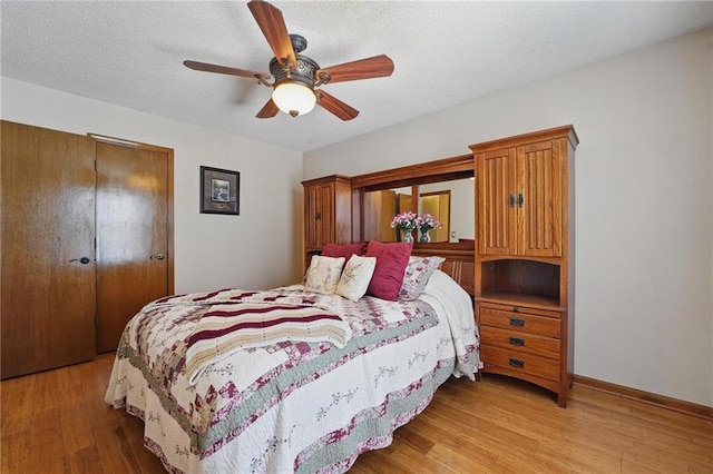 bedroom with a closet, light wood-style flooring, ceiling fan, and baseboards