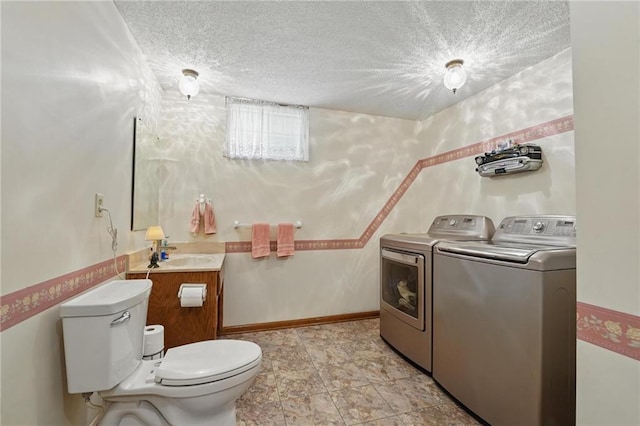 half bathroom with toilet, a textured ceiling, washing machine and dryer, and a sink