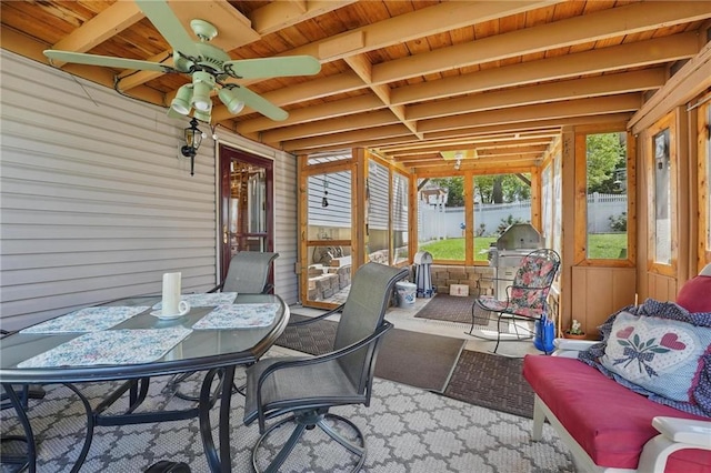 sunroom with a ceiling fan, outdoor dining space, an outdoor living space, and beamed ceiling