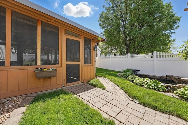 view of outdoor structure featuring fence and a sunroom