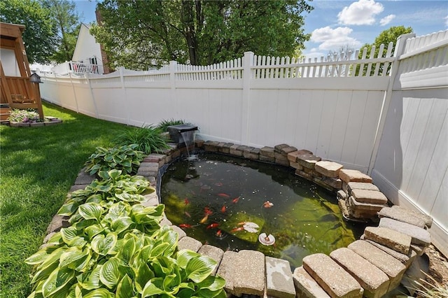 view of yard featuring fence and a garden pond