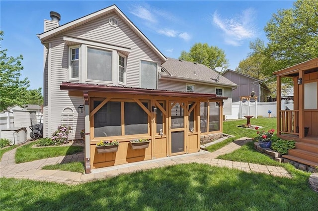 back of house featuring a sunroom, fence, a yard, and a chimney