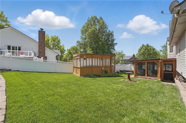 view of yard featuring a storage shed, an outbuilding, a fenced backyard, and a sunroom