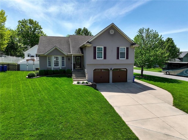 split level home featuring fence, an attached garage, driveway, and a front yard