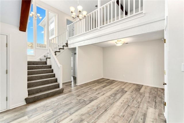 9738 Nieman Pl, Overland Park, KS 66214 - unfurnished living room with wood finished floors, stairway, baseboards, an inviting chandelier, and a high ceiling