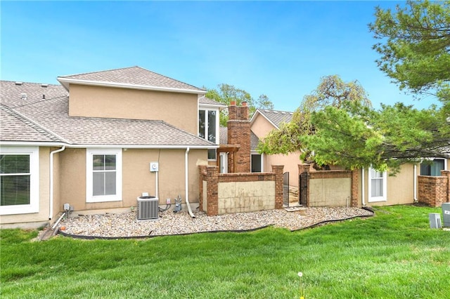 9738 Nieman Pl, Overland Park, KS 66214 - back of house featuring an attached garage, stucco siding, central AC unit, a chimney, and a yard