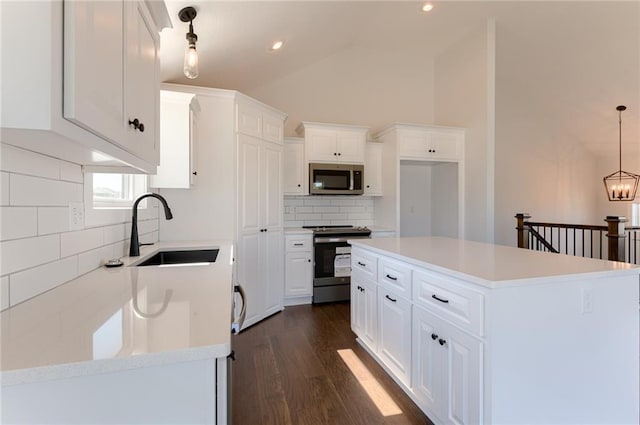 1308 N Holland Dr, Independence, MO 64056 - kitchen with stainless steel appliances, a sink, backsplash, dark wood-type flooring, and white cabinets
