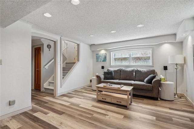 5101 NW Downing St, Blue Springs, MO 64015 - living room featuring a textured ceiling, light wood-type flooring, stairs, arched walkways, and baseboards