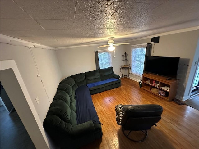 living area featuring baseboards, a ceiling fan, and wood finished floors