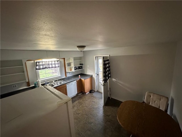 kitchen with a textured ceiling, open shelves, dark countertops, dishwasher, and a sink