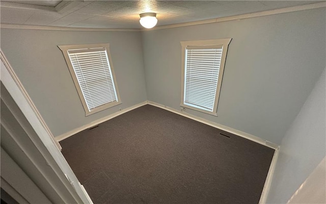 empty room with ornamental molding and dark carpet