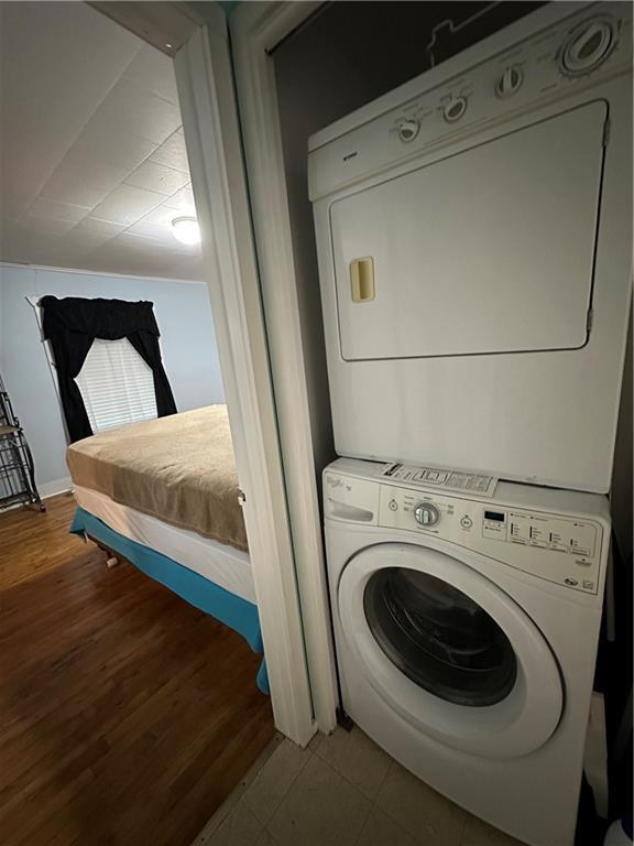 clothes washing area featuring stacked washer and dryer, laundry area, and wood finished floors