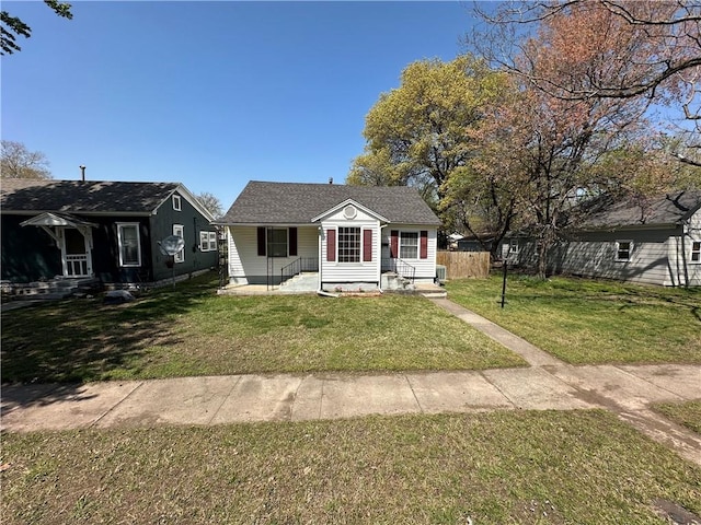 bungalow featuring entry steps, fence, and a front lawn