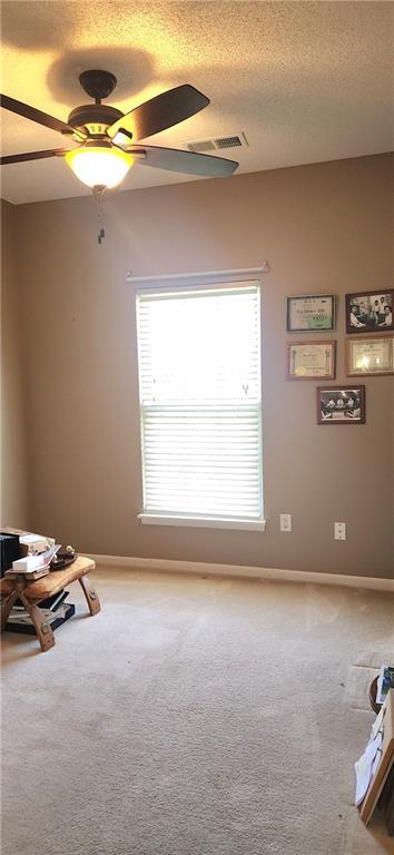 1219 S 3rd St, Louisburg, KS 66053 - unfurnished room featuring ceiling fan, light colored carpet, plenty of natural light, and a textured ceiling
