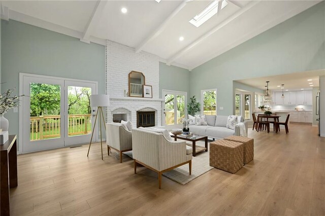 living room featuring light wood finished floors, a fireplace, beam ceiling, and high vaulted ceiling