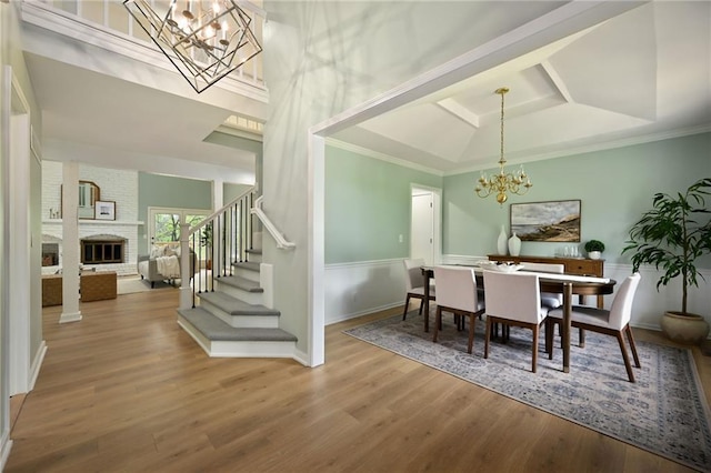 dining space with crown molding, stairs, wood finished floors, and a chandelier