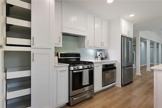 kitchen featuring appliances with stainless steel finishes, light wood-type flooring, light countertops, white cabinets, and recessed lighting