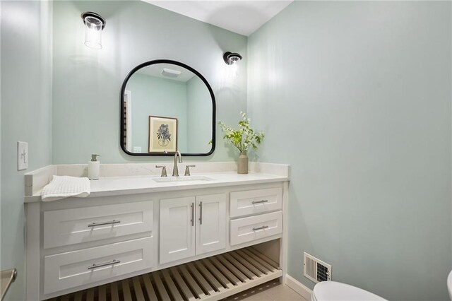 half bath with vanity, tile patterned flooring, toilet, and visible vents