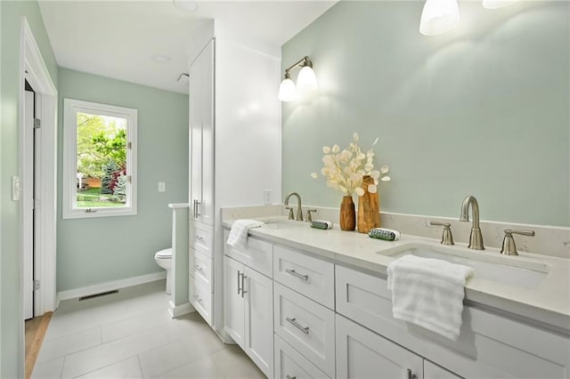 bathroom featuring double vanity, toilet, visible vents, and a sink