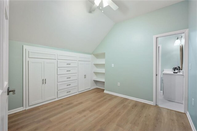 unfurnished bedroom featuring light wood-type flooring, baseboards, and vaulted ceiling
