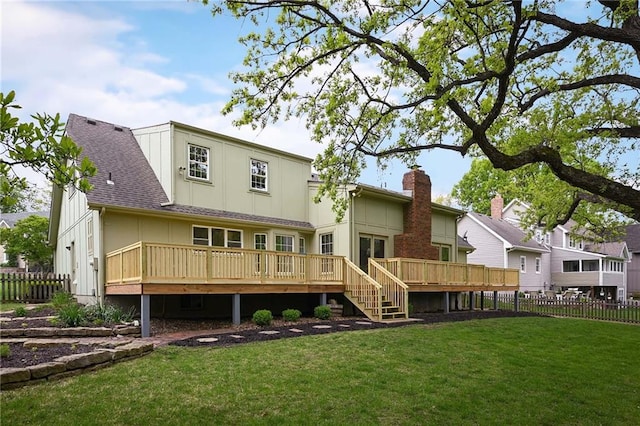 back of house with fence, a wooden deck, and a lawn