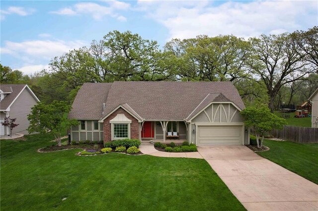 view of front of property featuring a porch, driveway, a front yard, fence, and an attached garage
