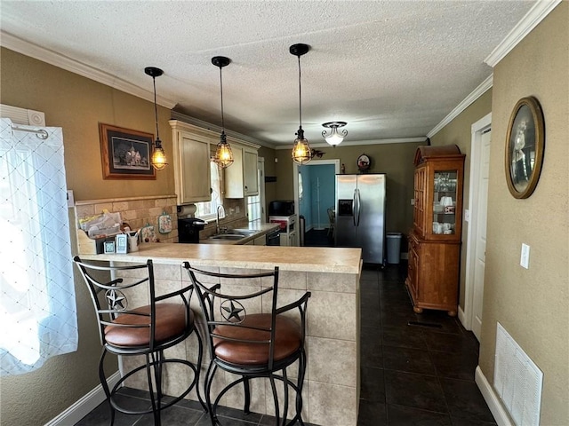 kitchen with stainless steel fridge with ice dispenser, visible vents, a sink, light countertops, and a peninsula