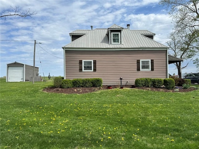 view of home's exterior with metal roof, a detached garage, a standing seam roof, and a lawn